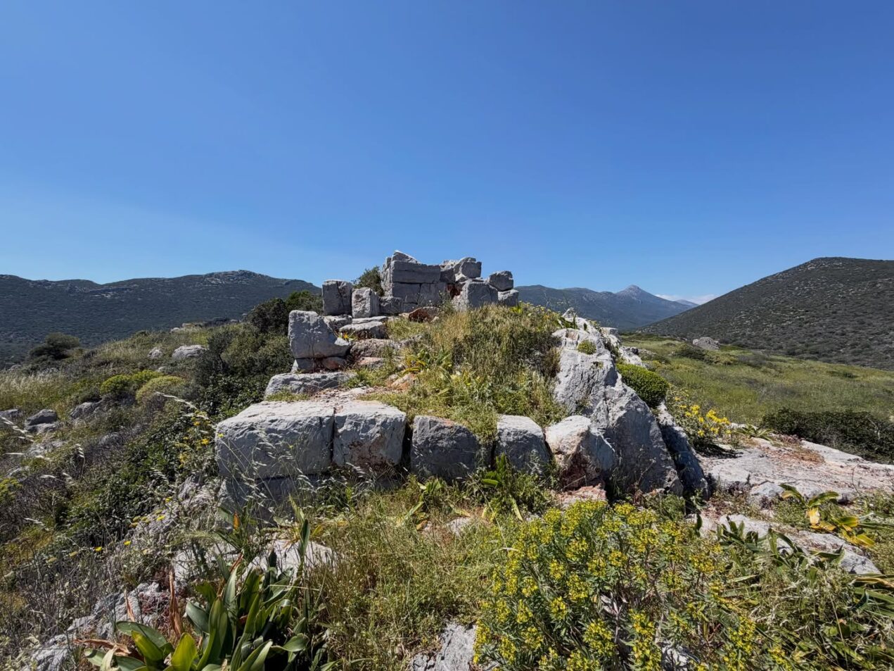 Ancient stone ruins surrounded by mountains and wild vegetation in Zarakas