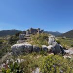 Ancient stone ruins surrounded by mountains and wild vegetation in Zarakas