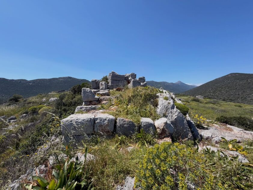 Ancient stone ruins surrounded by mountains and wild vegetation in Zarakas