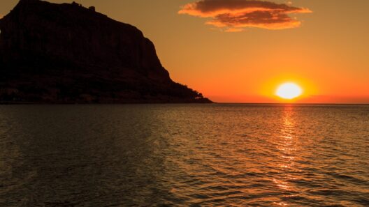 Monemvasia Castle silhouetted against a golden sunset over the sea